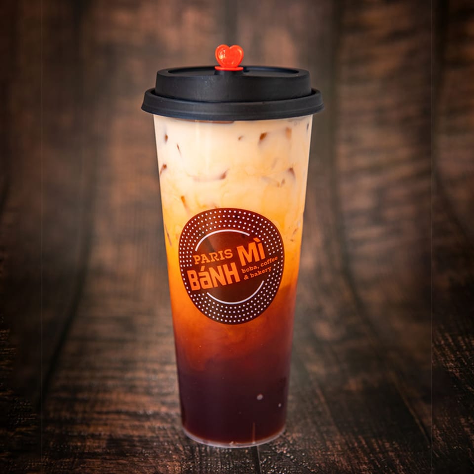 Paris Banh Mi Thai tea with milk and ice, topped with a red heart stopper.