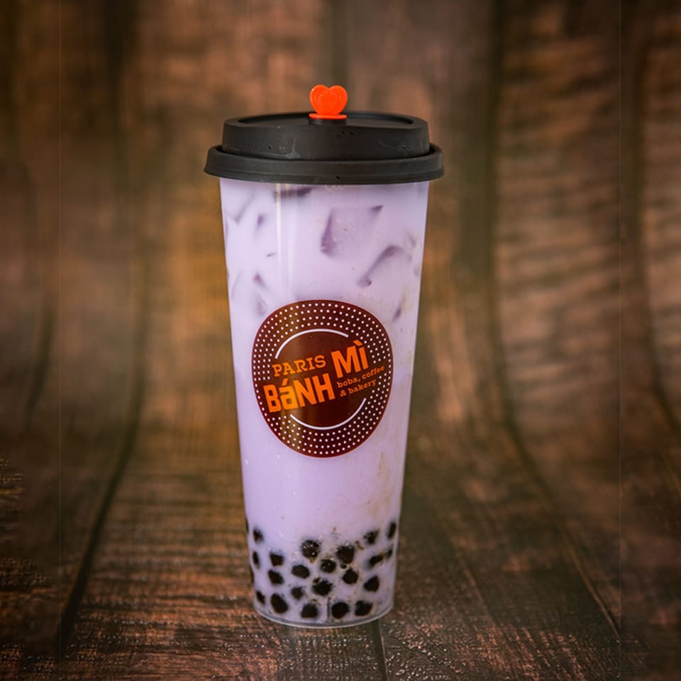Paris Banh Mi taro boba tea with a heart-shaped stopper on a wooden background.