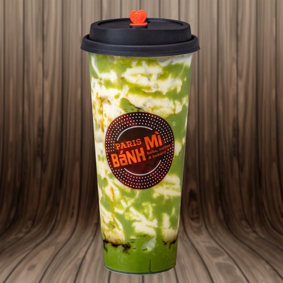 Paris Banh Mi's vibrant green and white matcha drink with a black lid and orange heart stopper.